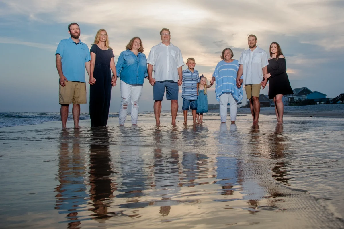 Orange beach photographer Sample Photos 13 Family photo standing on the edge of the water with their reflections in the water. Orange Beach, Alabama