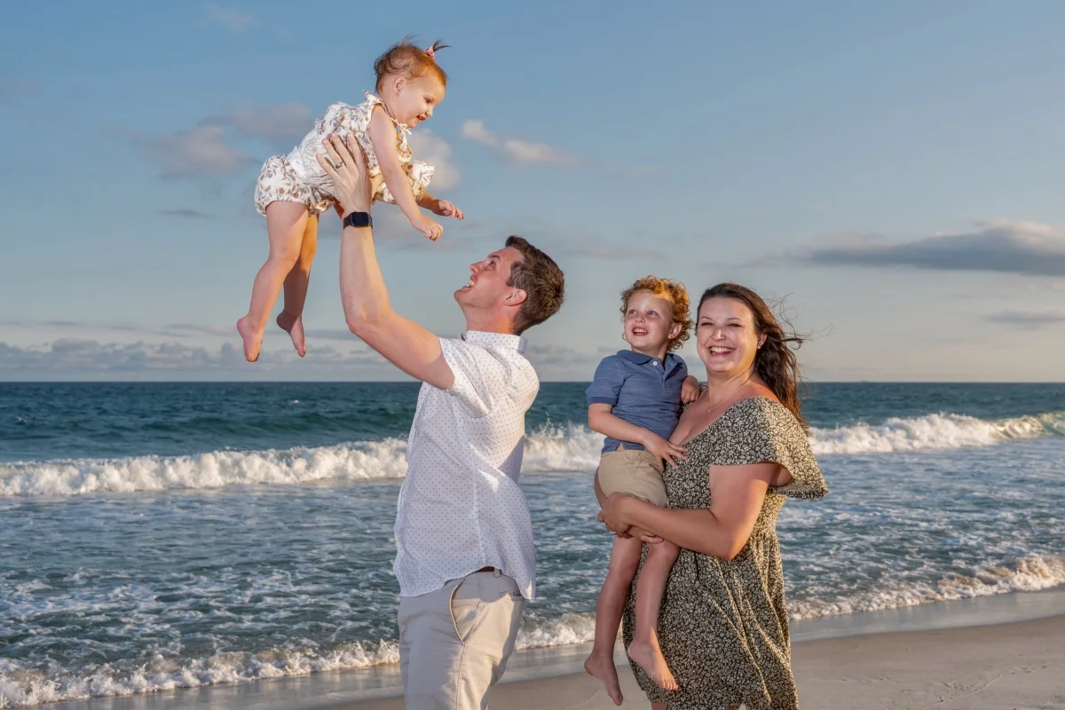 Orange beach photographer Sample Photos 18 Mom and Dad and two kids standing by the water's edge in Orange Beach, Alabama during a photo session.