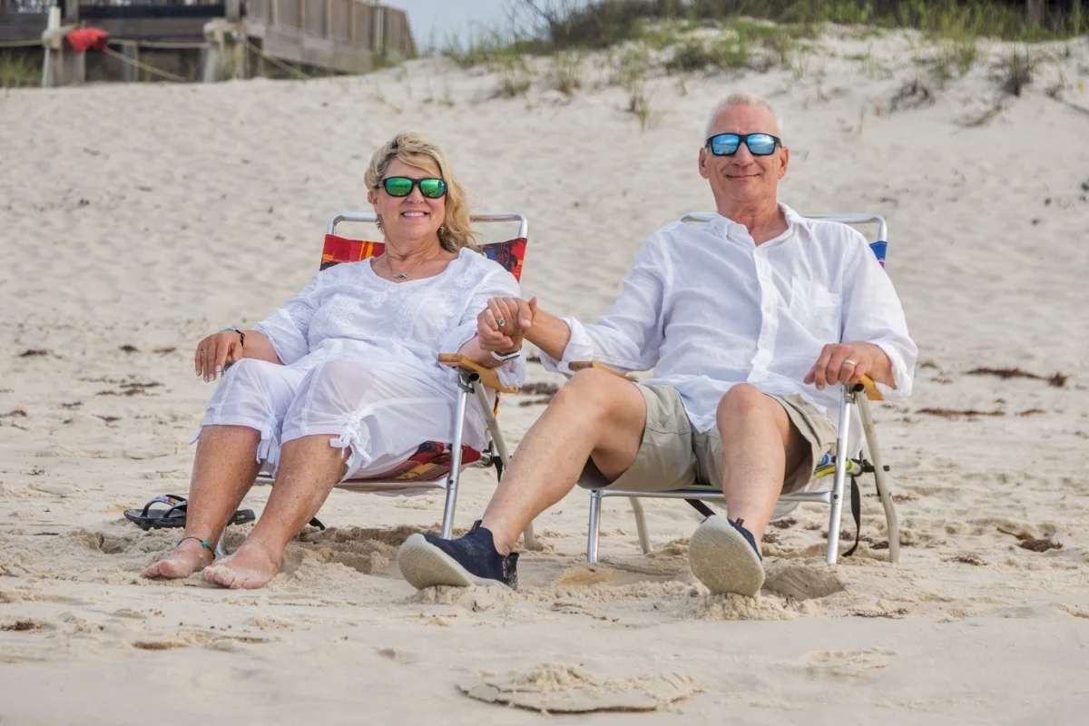 Couple sitting on the beach in chairs looking out at the ocean during an Orange Beach photo session.